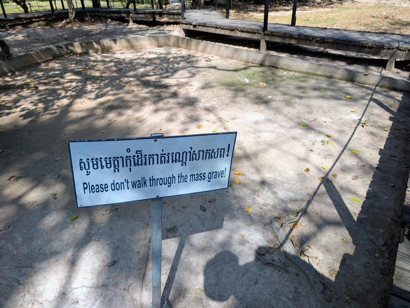 A sign reading "please don't walk through the mass grave!"