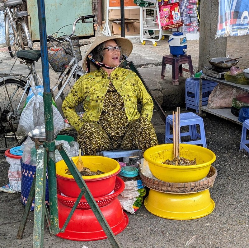 woman in yellow selling seafood from yellow buckets