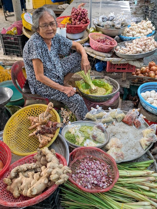 Woman in patterned loose cotton selling lemongrass and other herbs